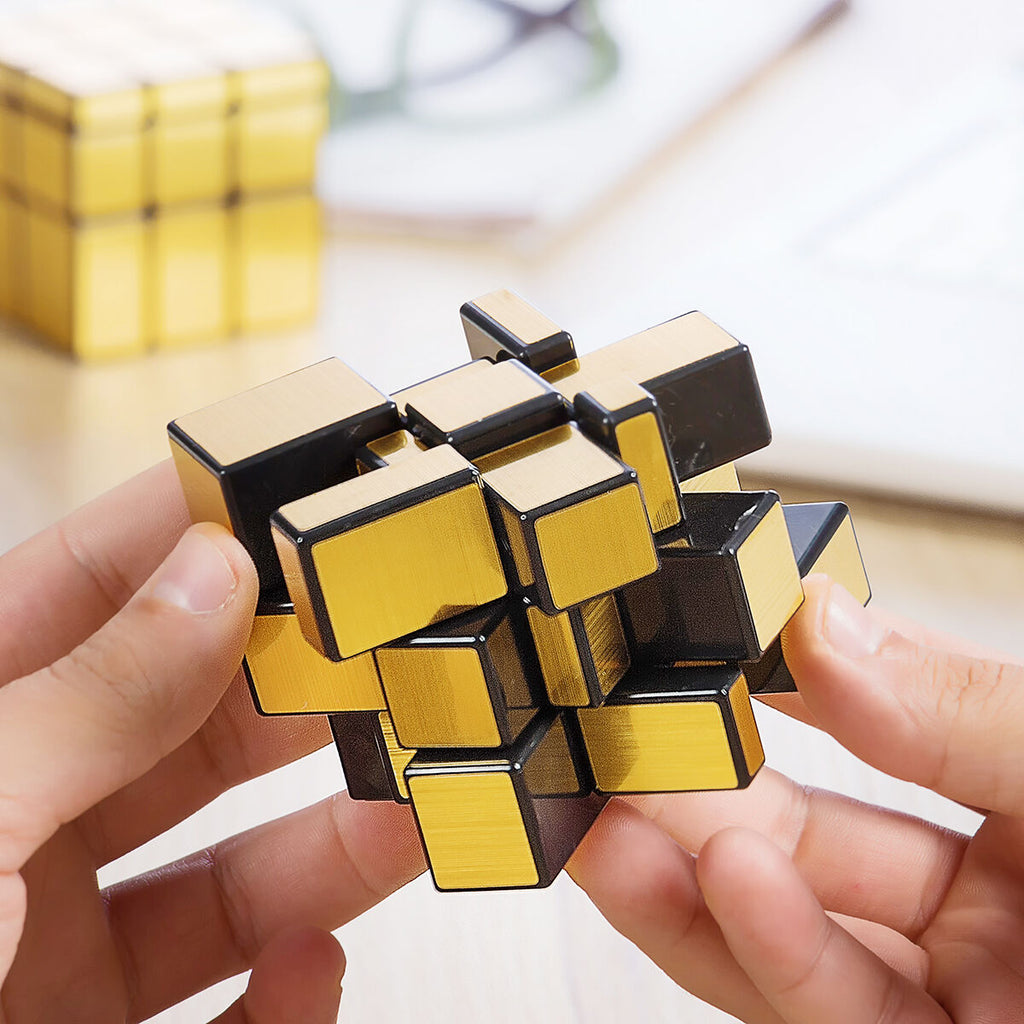 Gold and black puzzle cube held by a person with a blurred background